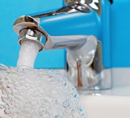 Glas wird unter Wasserhahn mit Trinkwasser befüllt